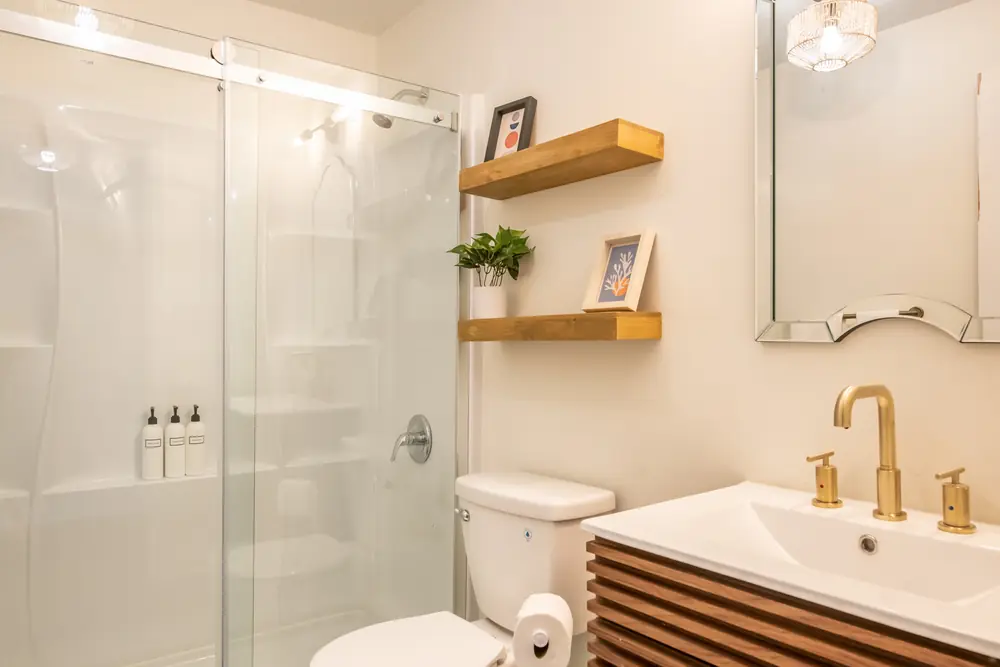 Unit B bathroom with a glass shower and gold faucet